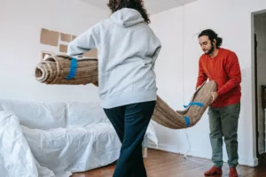 two people removing an old carpet from a home